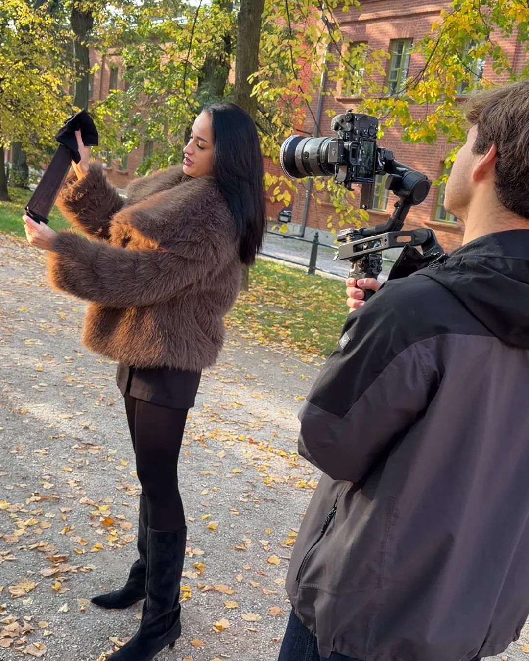Damian filmuje modelkę z produktem w jesiennym parku