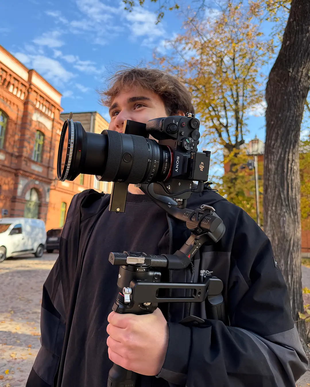 Damian Sokołowski z kamerą Sony na gimbalu na tle ceglanego budynku